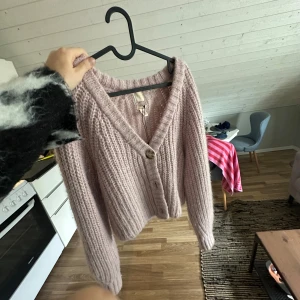 Ljusrosa stickad kofta från H&M, alpaca  - Supermysig ljusrosa stickad kofta från H&M med v-ringning och stora knappar framtill. Koftan har lång ärm och är gjord i en fluffig alpackablandning som känns extra mjuk och varm. Perfekt att slänga på sig när det är kyligt ute.