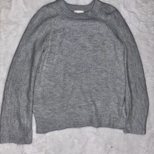 Grå stickad tröja med rund hals - En enkel och stilren grå stickad tröja med rund halsringning och långa ärmar. Perfekt för lager-på-lager och passar till allt. Mjuk och skön känsla, ribbade muddar vid ärmslut och nederkant.