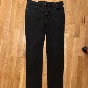 Svarta jeansbyxor med rak passform - Svarta jeansbyxor med klassisk femficksdesign och slim fit. Byxorna har dragkedja och knappstängning fram, samt bälteshällor. Materialet är jeans och färgen är helsvart, vilket ger en clean och stilren look.