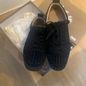 Christian Louboutin svarta med spikes Str 42 - Svarta sneakers från Christian Louboutin med  nitar på tån och klassisk röd sula. Strl 42. Skriv vid minsta fundering. Låda och nitar kommer med! Kom med prisförslag