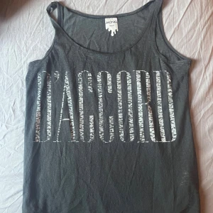  linnetopp från Monki  - Grå linnetopp från Monki i storlek XS med stort vitt tryck 'D'ACCORD' framtill. Tunn och mjuk bomullskvalitet, klassisk rund hals och smala axelband. 