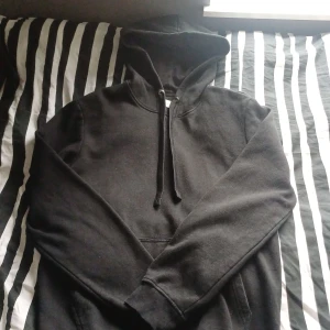 Svart hoodie från Pier One - Svart hoodie från Pier One med klassisk huva och snörning. Tröjan har en stor magficka och långa ärmar med ribbade muddar. Perfekt för en chill och avslappnad stil. Materialet känns mjukt och bekvämt, troligen bomull eller bomullsblandning.