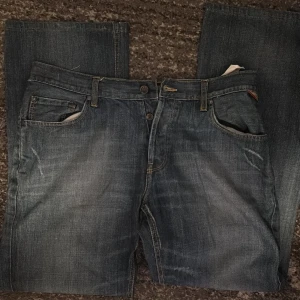 Blå jeans från TDK, modell Grand - Snygga blå jeans från TDK i modellen Grand. Jeansen har klassisk femficksdesign, raka ben och coola kontrastsömmar på bakfickorna. Materialet är slitstarkt denim i bomull och passformen är normal. Perfekta för dig som gillar en tidlös jeanslook.