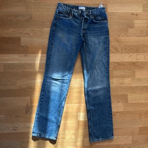Blå raka jeans från Zara - Klassiska blå jeans från Zara med rak passform och normal midja. Jeansen har fem fickor, knappgylf och subtila slitningar för en avslappnad look. Perfekta till sneakers eller boots. 