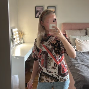 Mönstrad blus från Gina Tricot - Säljer pga att den inte kommer till användning, en färgglad blus från Gina Tricot i storlek 34. Puffiga korta ärmar med resår och rund halsringning. 