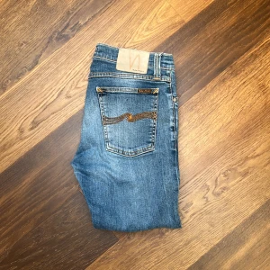 Blå jeans från Nudie Jeans - Säljer dessa cropped nudie jeans i storlek 29/32  Obs! Jeansen är avklippta, uppsydda, alltså kortare än förväntat  Längd: 81 cm  Bredd:39