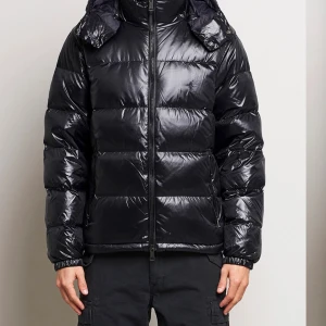 Svart pufferjacka från Polo Ralph Lauren - Säljer en svart pufferjacka från Polo Ralph Lauren med glansig finish och broderad logga på bröstet. Jackan har huva, dragkedja framtill och quiltad design. Perfekt för kalla dagar. Säljs inte längre vad jag vet men köpt på NK för 6000kr skriv om ni är intresserade så skickar jag bilder. Priset är ej hugget i sten