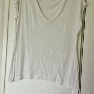 Vit topp från Sisters Point - Vit topp från Sisters Point i storlek L. Modellen är enkel med korta ärmar och rund halsringning. Perfekt basic-plagg att ha i garderoben. Det finns en liten prick på toppen vänstra sida (se bild).
