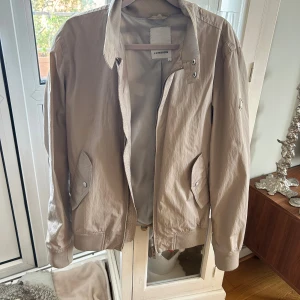 jacka från J.Lindeberg - beige vindjacka från J lindeberg, den enda defekten är att det är lite vit färg på loggan som man ser på sista bilden, storlek S, kan gå ner i pris vid snabb affär 