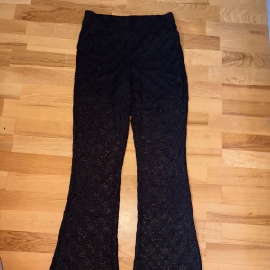 Svarta spetsbyxor med bootcut - Snygga svarta byxor i spets med bootcut-modell. Byxorna har hög midja och ett mönstrat spetsmaterial som ger en unik look. Svart, korta inbyggda shorts. 🌸