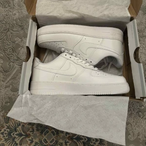 Nike Air Force 1 helvita sneakers - Klassiska Nike Air Force 1 sneakers i helvitt skinn. Har aldrig använts, säljs pågrund av att det inte passade min son, köpta från zalandö för ca 1400kr, kvitto finns 