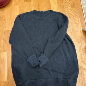 Mörkblå stickad tröja Brandy Melville - Mysig mörkblå stickad tröja från Brandy Melville med rund halsringning och ribbade muddar vid ärmslut och nederkant. Perfekt för lager-på-lager och chill dagar. Enkel och stilren design som passar till det mesta.