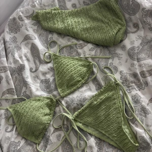 Grön ribbad bikini med snörning - Snygg ljusgrön bikini med ribbad struktur och trendiga knytband i sidorna. Triangeltopp och klassiska bikinitrosor med pareo.