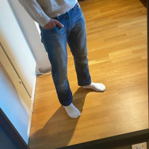 Blå jeans från Diesel Industry - Säljer ett par klassiska blå jeans från Diesel Industry med snyggt slitna detaljer och raka ben. Jeansen har normal passform, fem fickor och tydliga kontrastsömmar. Perfekta för dig som gillar en avslappnad och tidlös stil. Priset är inte hugget i sten. 