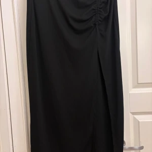 Svart långkjol med slits  - Säljer en svart långkjol med en slits framtill. Kjolen har en elegant och stilren look men är tyvärr för liten för mig, använd ett fåtal gånger