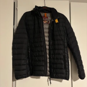 Svart lättviktsdunjacka Parajumpers M - Säljer en svart quiltad lättviktsdunjacka från Parajumpers i storlek M. Jackan har dragkedja framtill, två sidofickor med dragkedja och en gul detalj vid kragen. perfekt för kyliga dagar.