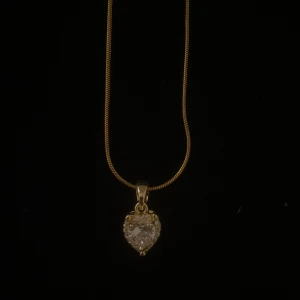Guldhalsband med hjärtformad berlock - Ett elegant halsband i guld med en tunn kedja och en gnistrande hjärtformad berlock. Berlocken är dekorerad med klara stenar som ger ett lyxigt intryck. Perfekt accessoar för att lyfta vilken outfit som helst.