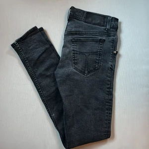 Svarta slim jeans Tiger of Sweden - Svarta jeans från Tiger of Sweden i modellen Slim. Jeansen har klassisk femficksdesign, snygg tvättad finish och smal passform. Tillverkade i mjukt denimtyg med svarta sömmar och läderpatch i midjan. Perfekta för dig som gillar stilrena och moderna jeans.