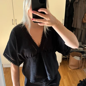 Svart blus med spetsdetaljer - Svart blus med v-ringning och korta, vida ärmar. Fina spetsdetaljer längs urringningen och vid ärmarna. Blusen är från Zara och använd fåtal gånger! I fint skick🙌🏼
