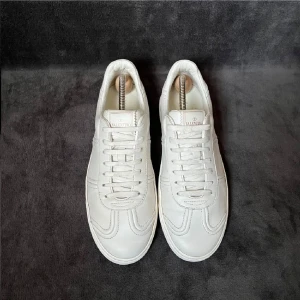 Valentino vita skinnsneakers - Snygga vita sneakers från Valentino i skinn med klassisk låg siluett. Skorna har snörning och diskreta nitar på hälen som ger en cool touch. Perfekta för dig som gillar stilrena och exklusiva sneakers med en twist.