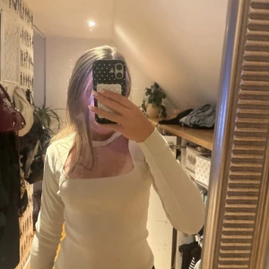 Vit långärmad topp med cut out från Zara - Säljer en vit långärmad topp från Zara med fyrkantig urringning och snygg cut out-detalj vid halsen. Toppen är i mjukt, stretchigt material och har en smickrande passform. Perfekt för dig som gillar trendiga och stilrena plagg.