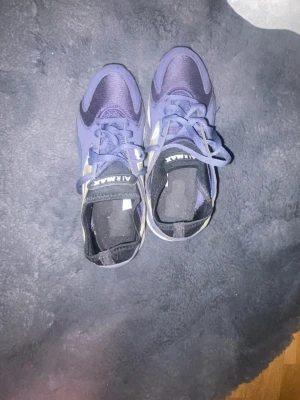 Nike Air Max sneakers lila/gul - Nike Air Max sneakers i lila och gult med vit sula och synlig Air Max-bubbla. Skorna har snörning, mesh- och syntetpaneler samt klassisk Nike Swoosh i gult på sidorna. Perfekta för dig som gillar sportig och färgstark stil.