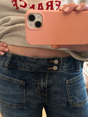 Blå jeans med raka ben och stora fickor - Jätte snygga blå jeans med raka ben och stora fyrkantiga fickor framtill. Jeansen har låg midja, dubbla silverknappar och klassiska sömmar. De är baggy bootcut modell i storlek S🩷