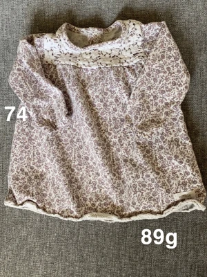 Blommig klänning från Newbie - Supersöt blommig klänning från Newbie i ljusa toner med lila blommönster och spetsdetaljer upptill. Långärmad modell, perfekt för vår och sommar. Söt och bekväm passform för de minsta.🌸 Fint använt skick. Storlek 74