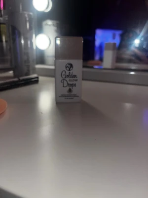 W7 Golden Glow Drops highlighter - Flytande highlighter från W7 i färgen Golden Glow Drops. Kommer i en liten vit plastflaskas med guldigt lock. Perfekt för att ge ansiktet en snygg glow och highlighta kindbenen. Enkel att applicera och ger ett skimrande resultat.