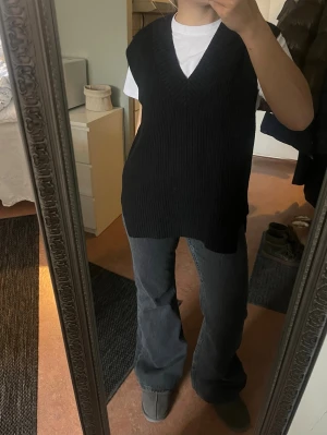 Svart stickad väst från H&M - Säljer en svart, ribbstickad väst från H&M i storlek S. Västen har v-ringning, är lite oversized och har slitsar i sidorna. 