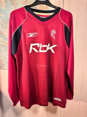 Bolton Wanderers Reebok 2006/08 away longsleeve shirt, storlek L - Good condition.#boltonwanderers #bolton #premierleague #anelka #nolanRöd långärmad tröja med tryck av Reebok och Bolton Wanderers 