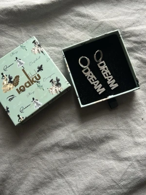  DREAM örhängen i silver från iouku  - Säljer ett par silvriga örhängen fårn iouku i nyskick endast testade på! Säljer dessa pågrund av att jag personligen tyckte dom var för stora för mig. Ask följer med, skriv vid intresse❤️