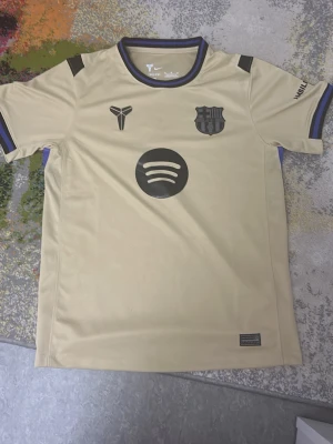 Barcelonas borta tröja - En skit snygg Barca tröja med printen spotify och nine logan och barca logan bra för fotbollsfansen!