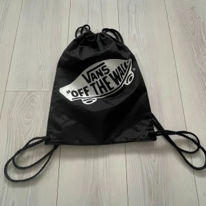 Svart gympåse från Vans - Säljer en svart helt ny oanvänd gympåse från Vans med det klassiska 'Off The Wall'-trycket i vitt framtill. Vid intresse bara att höra av sig! 