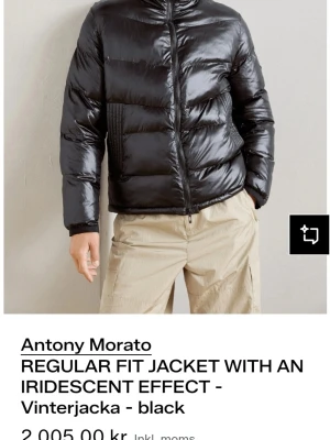 Svart pufferjacka från Antony Morato - Snygg svart pufferjacka med glansig finish och iriserande effekt från Antony Morato. Jackan har hög krage, dragkedja framtill och quiltade partier. Perfekt för kalla dagar när du vill hålla stilen och värmen.