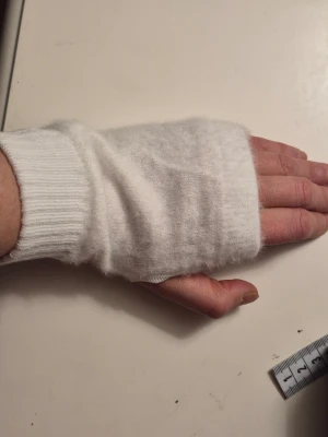  Helt nya Vita stickade handledsvärmare - Mysiga handledsvärmare i fluffigt vitt stickat material. De har tumhål och ribbade muddar för extra komfort. Perfekta för att hålla händerna varma under kyliga dagar och ger en enkel, clean look.