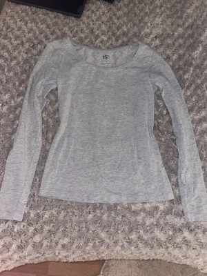 Ljusgrå långärmad topp från 157 - En basic ljusgrå långärmad topp från 157 med rund halsringning. Tillverkad i mjuk bomullsblandning med lite stretch för skön passform. Perfekt att styla till jeans eller kjol för en enkel och clean look.
