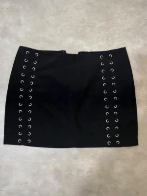 Svart kortkjol med snörning - Snygg svart kortkjol med cool snörningsdetalj på båda sidor framtill💕