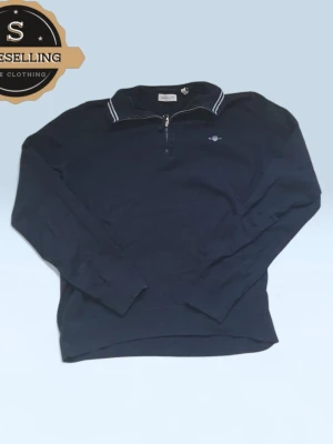 Marinblå half zip tröja från GANT - Snygg marinblå långärmad tröja från GANT med half zip och broderad logga på bröstet. Tröjan har en krage med vita ränder och är gjord i mjuk bomull. Perfekt för en chill och stilren look.