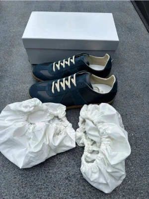 Blå sneakers från Maison Margiela - Säljer ett par stilrena blå sneakers från Maison Margiela, allt på bilden fås med. Dem är använda en gång.