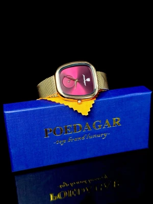 Poedagar Éclat Rubis – Woman’s Collection  - Poedagar Éclat Rubis – Woman’s Collection är en elegant och stilren armbandsklocka i exklusiv guldfinish. Klockan har en modern fyrkantig boett och en vacker urtavla i djup rubinrosa ton som ger ett lyxigt och sofistikerat uttryck. Det justerbara mesh-armbandet gör att klockan sitter bekvämt och passar de flesta handleder. Perfekt som vardagsklocka med det lilla extra eller som en uppskattad present. Levereras i originalask. Helt ny.