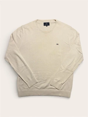 Beige stickad tröja från Lexington - Snygg beige stickad tröja i storlek L från Lexington med rund halsringning och diskret logga på bröstet. Tröjan har ribbade muddar vid ärmslut och nederkant, vilket ger en clean och klassisk look. Perfekt för lager på lager under höst och vår.