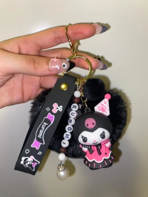 Nyckelring i hellokittyserien *innehåller kristaller* - En söt nyckelring med figur från hello kitty serien.  Ingår- Ett svart hjärta En figur från hellokitty serien En pärlad text där det står "kuromi" innehåller även kristaller.