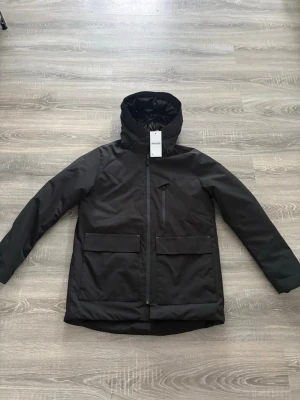 Svart vinterjacka från Jack & Jones - Säljer en svart vinterjacka från Jack & Jones med huva och stora fickor framtill. Jackan har dragkedja hela vägen och en extra bröstficka med dragkedja. Perfekt för kalla dagar och har en clean, stilren look. Den är lite liten i storleken.