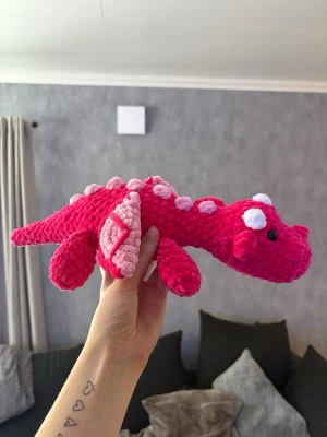 Virkad rosa drake 🐉💗 - Virkad rosa drake – handgjord & unik 🐉🩷En charmig och mjuk virkad drake i rosa toner, perfekt som present, inredningsdetalj eller gosedjur för större barn • Draken är stadig men samtidigt mjuk och kramvänlig, och passar lika bra i barnrummet som på hyllan eller sängen✨ 🐉Pris: 350kr 🐉OBS! ⚠️ Innehåller säkerhetsögon – rekommenderas ej till barn under 3 år.