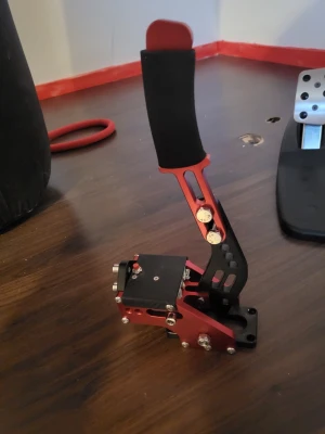 Sim Racing USB Handbrake - Robust USB handbroms för simracing, tillverkad i metall med röd och svart finish. Passar racingriggar och är kompatibel med PC. Ergonomiskt handtag med skumgrepp. Ser ut att vara i mycket gott skick utan synligt slitage eller defekter.