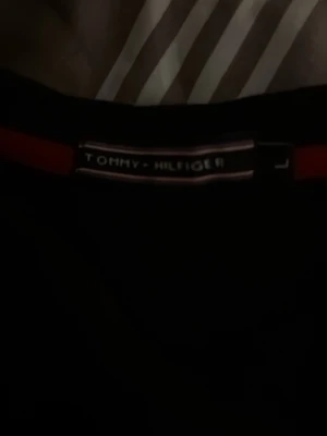 Svart sweatshirt från Tommy Hilfiger, priset kan diskuteras  - En stilren svart sweatshirt från Tommy Hilfiger med klassisk rund hals och diskret logga på bröstet. Tröjan har långa ärmar och är tillverkad i mjukt bomullsmaterial. Perfekt för dig som gillar enkel och tidlös design.