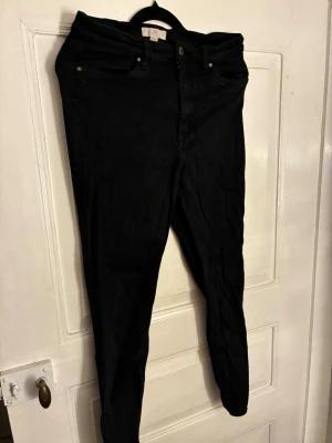 Svarta skinny jeans från H&M - Säljer ett par svarta skinny jeans från H&M i storlek 40. Jeansen har klassisk femficksdesign, bälteshällor och dragkedjegylf. Materialet är stretchigt och bekvämt, perfekt för dig som gillar en tight passform. Skulle säga att de passar storlek S/M.