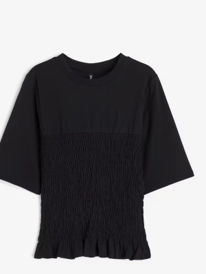 Svart topp med smock och volang - Säljer en svart topp med smockad midja och volangkant nedtill. Toppen har rund halsringning och korta ärmar i lös passform. Perfekt till jeans eller kjol för en chill look. Går inte att köpa längre.