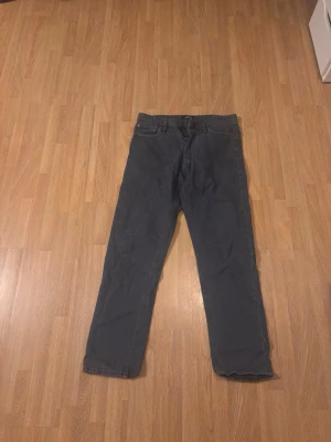 Mörkblå jeans från Jack & Jones, 31/32 - Säljer ett par mörkblåjeans från Jack & Jones i storlek 31/32. Klassisk femficksmodell med raka ben och knappgylf. Jeansen har en stilren look som passar till det mesta. Samma på denna finns en liten lagning mellan benen, men den är sydd med samma färg som smälter in. Inte så märkbart. Hör av er vid frågor. 